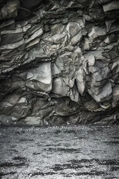 Basalt cliff with hexagonal plates above black sand beach in Iceland Stock Photos