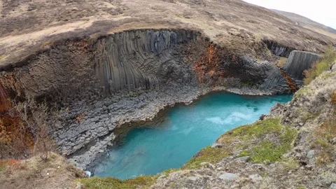 Basalt column walls above a turquoise pool in Studlagil, Iceland Stock Footage 346443992