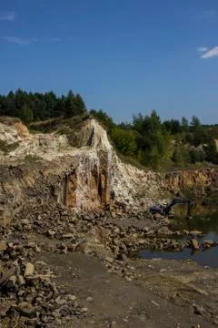 Basalt columns. Broken excavator and basalt columns rocks. Heavy industry Stock Photos
