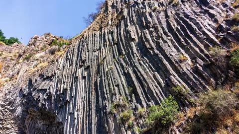 Basalt columns form dramatic cliffside under bright daylight Stock Photos
