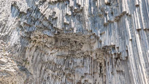 Basalt columns rise vertically against sunlit rock wall Stock Footage 341776157