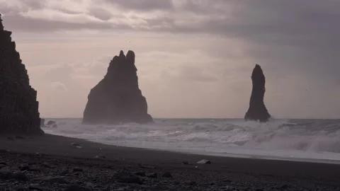 Basalt columns stand against crashing waves at Reynisfjara Beach in Iceland Stockbeeldmateriaal 329443158