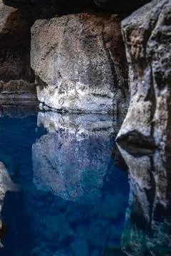 Basalt lava cave pool reflects walls in Iceland geothermal grotto Foto stock