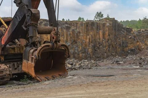 Basalt mining. Excavators in a basalt quarry near the forest. Stock Photos