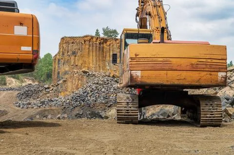 Basalt mining. Yellow excavators in a basalt quarry near the forest. Foto stock