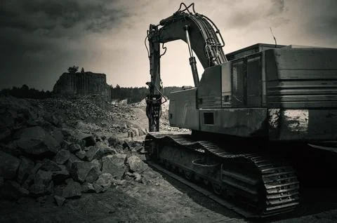 Basalt mining. Yellow excavators in a basalt quarry near the forest. Stock Photos