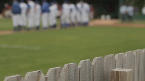 Base ball team on field during national anthem, blurred then focus on fence line Stock Footage