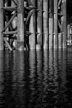 The base of the bridge is reflected in the water, the black and white photo Stock Photos