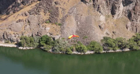Base jumper with bright yellow and red chute parachutes from the Perrine Bridge Stock Footage 215320030