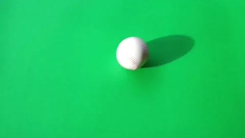 Baseball ball rolling on green background with shadow of baseball on backgrou Stock Footage 197033815
