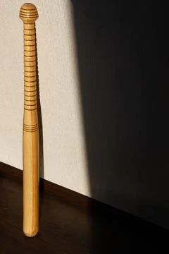 A baseball bat stands against the wall. Beautiful shadow of the sun Stock Photos