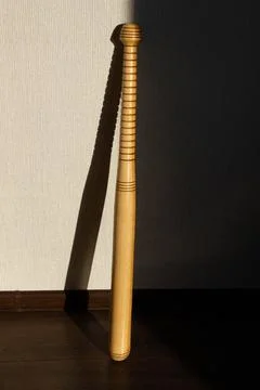 A baseball bat stands against the wall. Beautiful shadow of the sun Stock Photos
