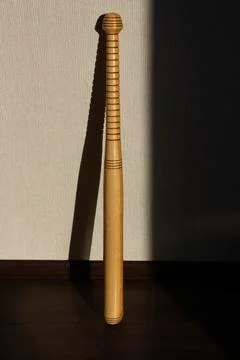 A baseball bat stands against the wall. Beautiful shadow of the sun Stock Photos