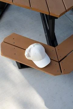 Baseball cap rests on picnic table in outdoor setting during sunny day Stock Photos