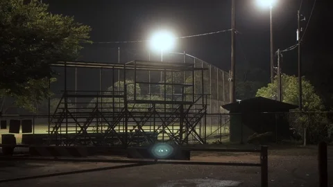 Baseball field small stadium at night with floodlights. Eerie dark football Vídeo Stock 113598790