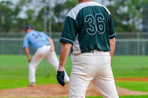 Baseball game, runner on the first base is watching the pitcher and getting.. Stock Photos