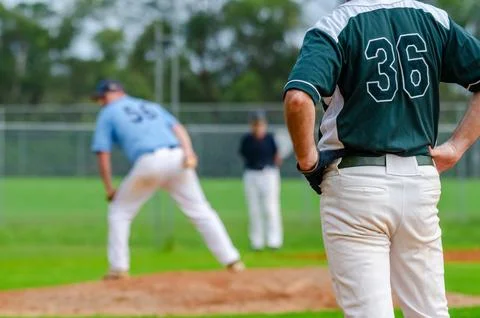 Baseball game, runner on the first base is watching the pitcher and getting.. Stock Photos