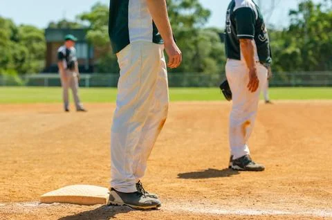 Baseball game, runner on the third base is watching the pitcher and getting.. Foto stock