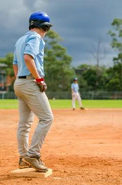 Baseball game, runner on the third base is watching the pitcher and getting.. Stock Photos
