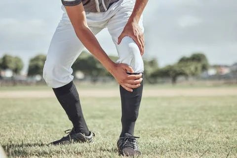 Baseball leg injury, man and sports athlete on a outdoor grass field hurt in the Stock Photos