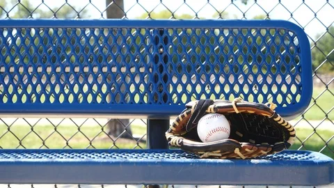 Baseball mitt and baseball sitting on a bench on a warm summer day, 4k, 60fps. Stock Footage 115849070