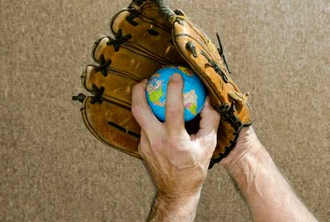 Baseball pitcher holding world globe in glove Stock Photos
