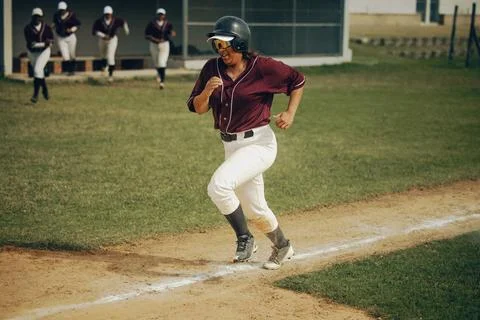 Baseball player aggressively running on base path aiming for home run durin.. Stock Photos