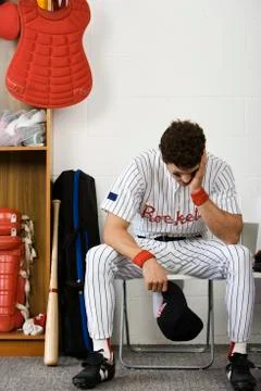 Baseball player sitting with head in hands in locker room Foto stock