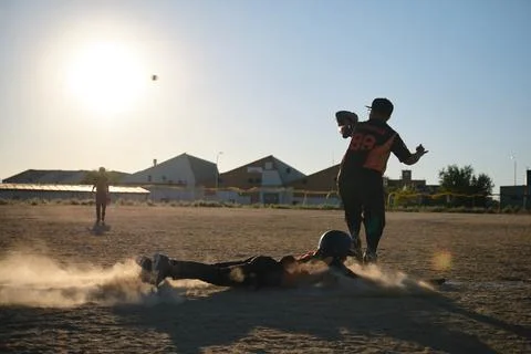 Baseball player sliding into base creating dust cloud Foto stock