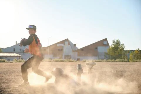 Baseball players sliding into base creating dust cloud Foto stock