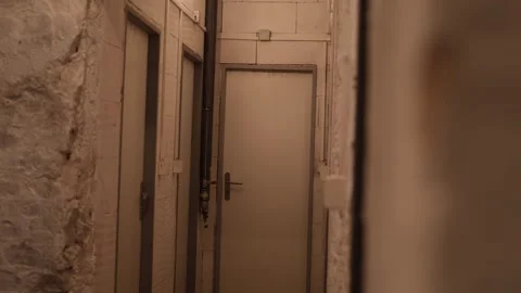 Basement corridor with white doors and exposed utility pipes in dim lighting cre Stock Footage 314519100