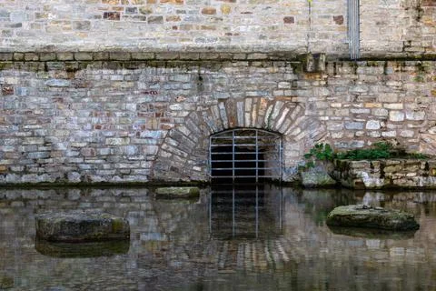 The basement curtained window of an ancient building is reflected in the wate Stock Photos
