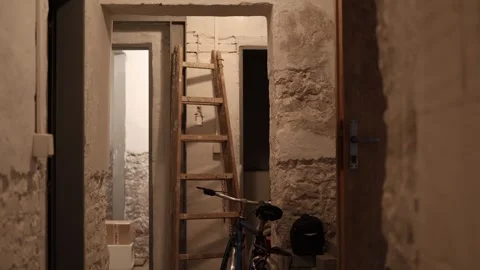 Basement hallway with rough stone walls a wooden ladder leaning against the wall Stock Footage 314519099