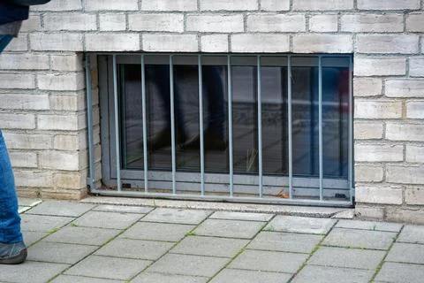 Basement level window with security bars near street close view Stock Photos