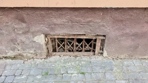 Basement Vent with Metal Grille in a Weathered Building Wall and Pavement Vídeos de archivo 346441279