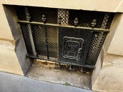 Basement window with iron grate and historic gas cover on limestone buildin.. Stock Photos