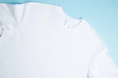 Basic folded white t-shirt blue background. Mock up for branding t-shirt. Cop Stock Photos