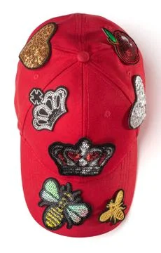 Basic red cap covered with various patches on white background Stock Photos