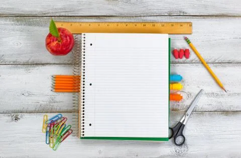 Basic school supplies with apple on white wooden desk Stock Photos