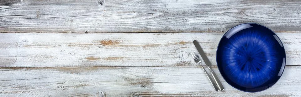 Basic table setting of an empty main dark blue dish with cutlery on wood Stock Photos