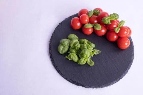 Basil and tomatoes on a stone tile Stock Photos