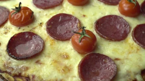 Basil falls on spinning tomato cherry and pepperoni pizza in slow motion Video stock 96858919