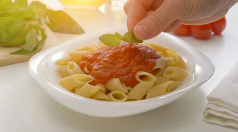 Basil leaf being put on freshly cooked homemade pasta with tomato souce Stock Footage 67997510