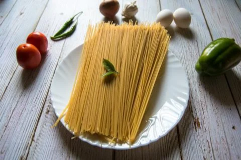 Basil leaf on raw spaghetti pasta. Stock Photos