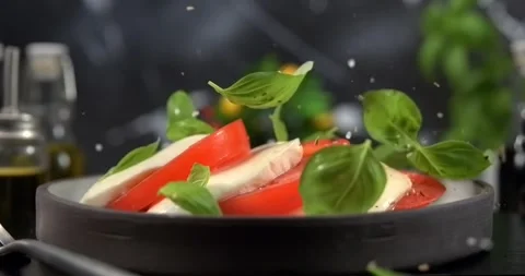 Basil leaves falling onto caprese salad on black background slow motion 1000 fps Stock Footage 346650843