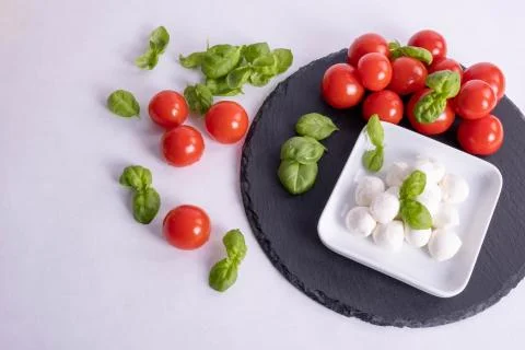 Basil, mozzarella and tomatoes on a table Stock Photos