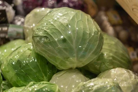 Basket with cabbage heads wrapped in plastic in shop Foto stock