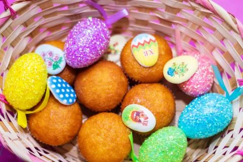 In the basket close-up colored Easter eggs and cupcakes, festive background Stock Photos
