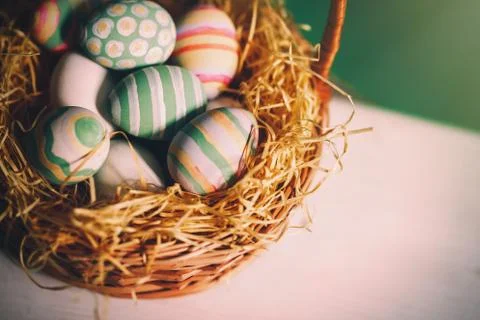 Basket with colorful Easter eggs, close up photo Stock Photos