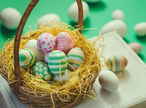 Basket with colorful Easter eggs, close up photo Stock Photos